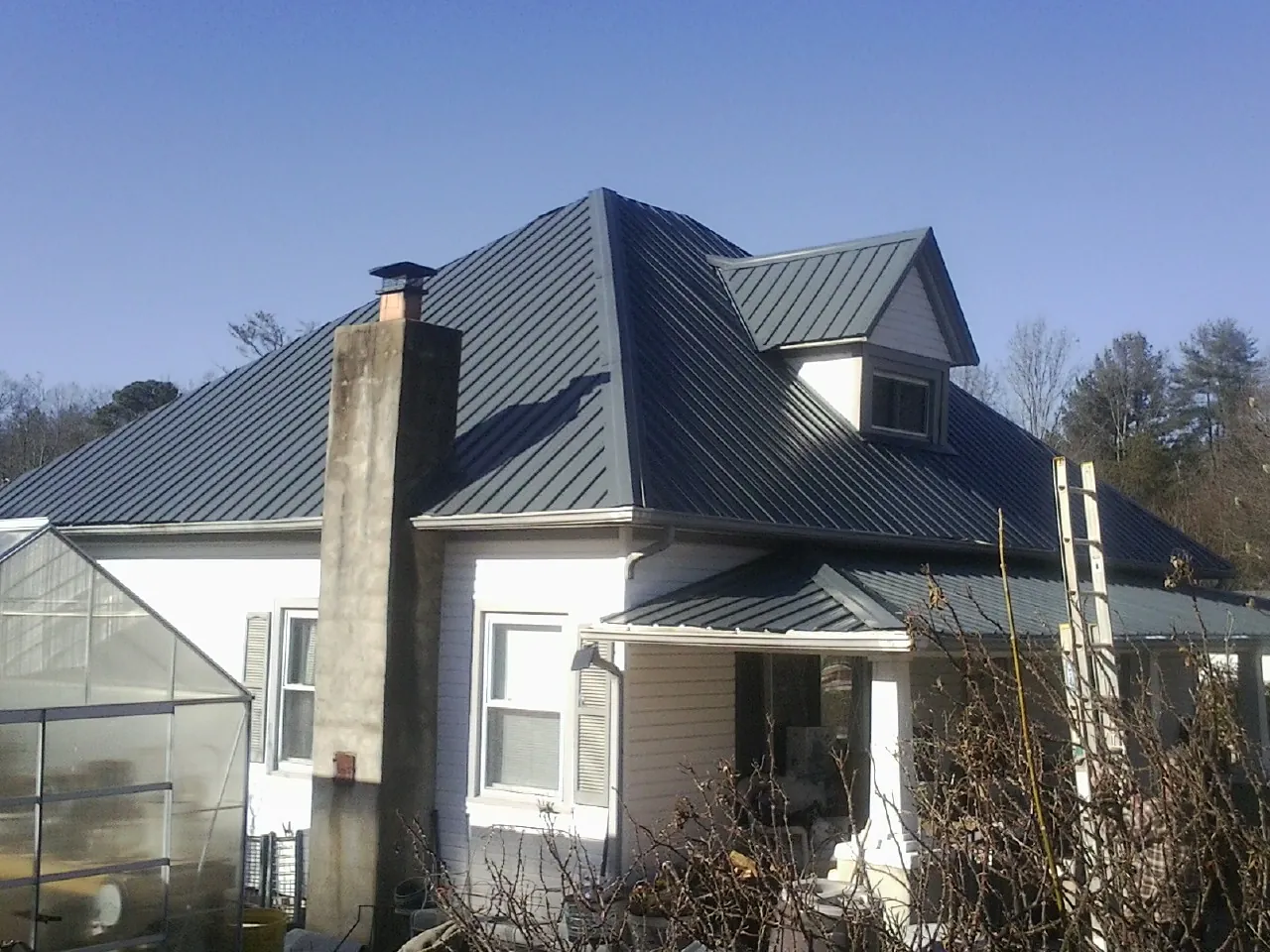 Dark blue standing seam metal roof on a white farmhouse with dormer — Slate & Tile Roof Repair by Roofing Brothers in New Harmony