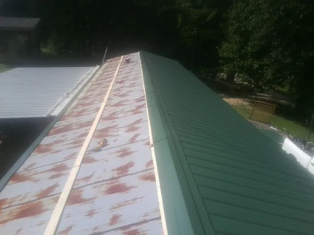 Old rusted panels beside newly installed green metal roofing — Wind Damage Roof Repair by Roofing Brothers in New Harmony