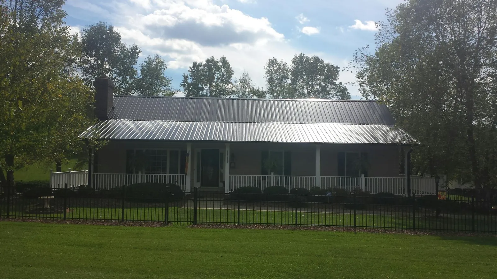 Gray metal roof on a brick ranch with a full width front porch — Gutter Guard Installation work by our crew in New Harmony
