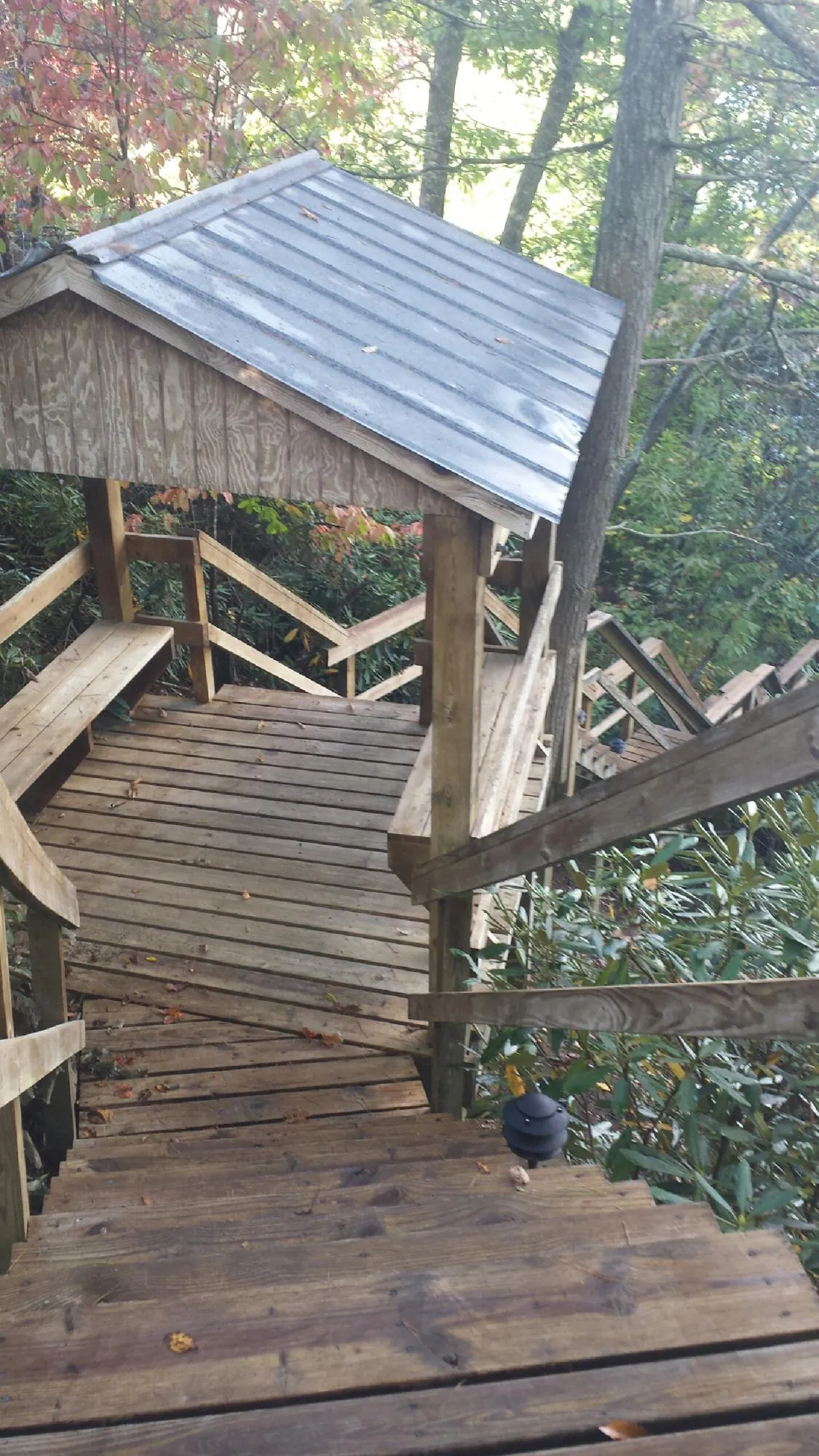 Metal roofed shelter over wooden steps on a wooded walkway — Skylight Repair & Installation work by our crew in New Harmony
