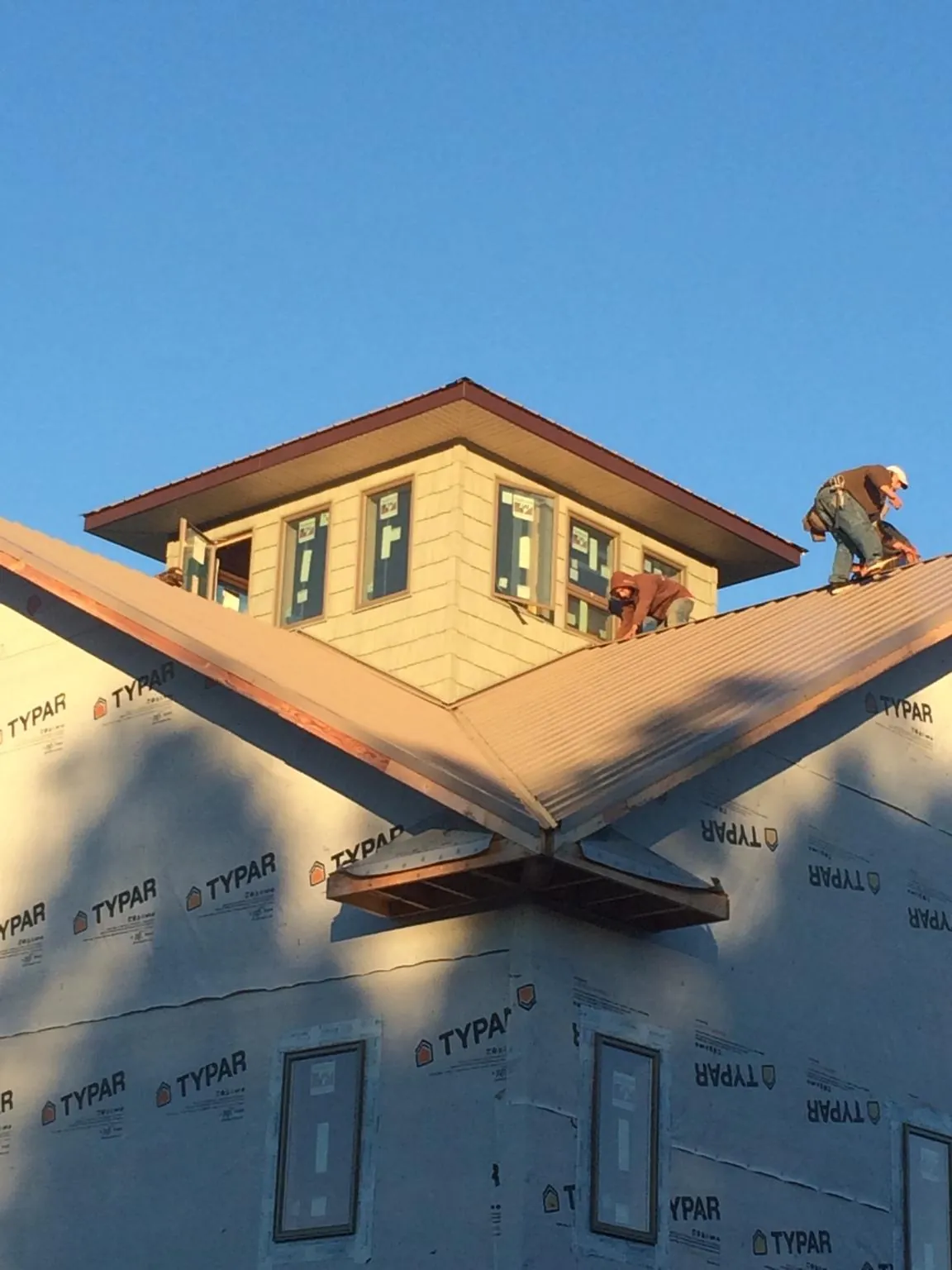 Roofers working around a rooftop cupola on a new metal roof at sunset — Roof Waterproofing in New Harmony by Roofing Brothers